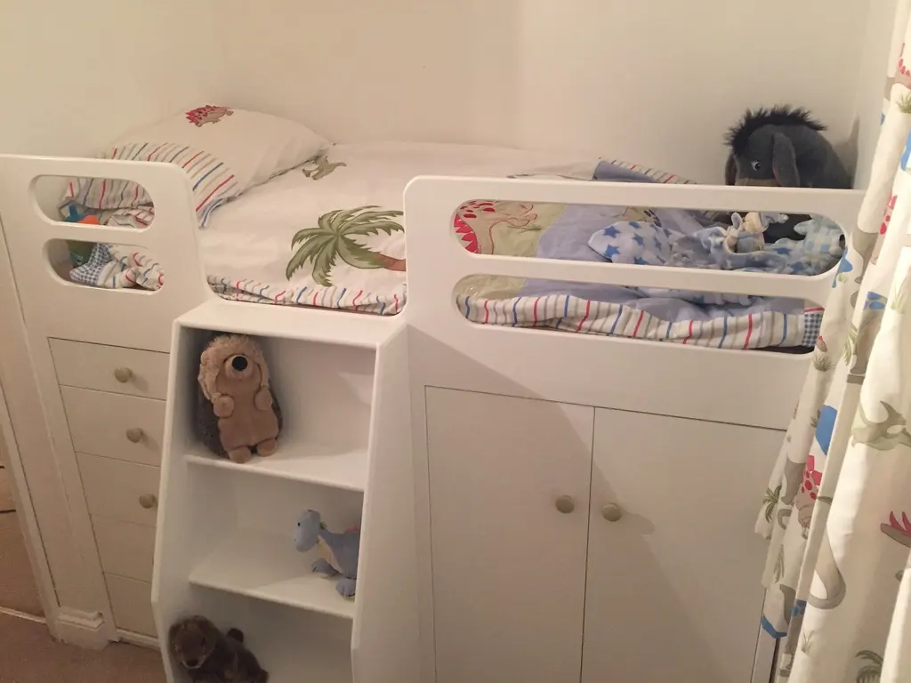 Finished white cabin bed with drawers, cupboard and step shelves, made up with bedding
