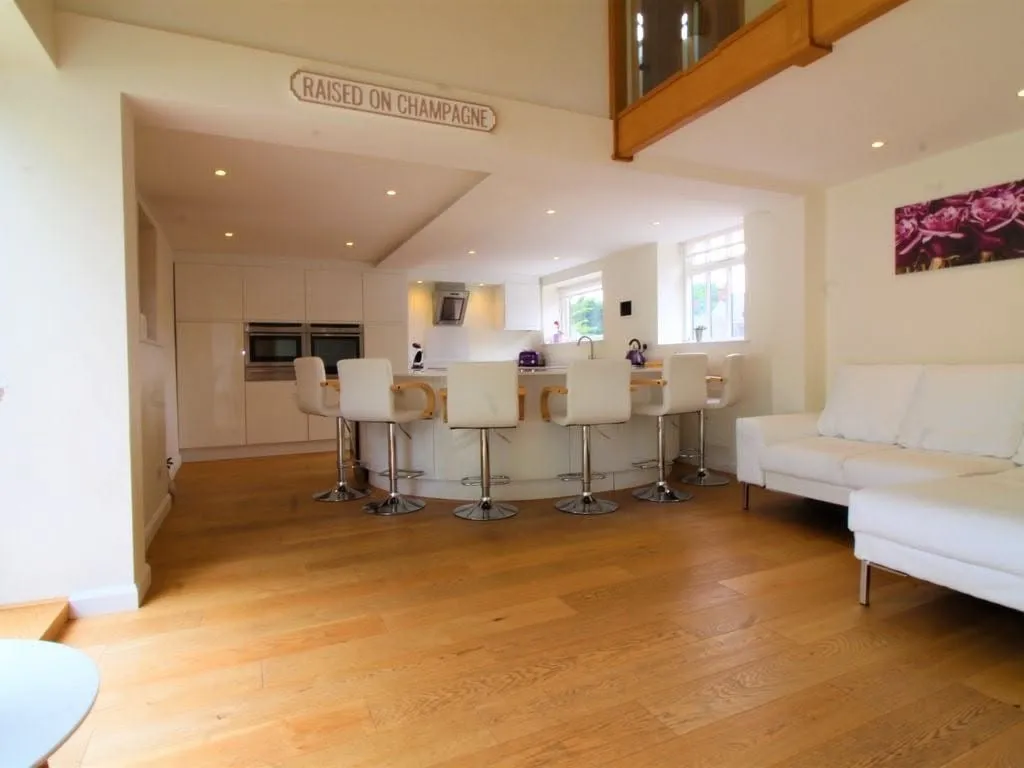 Open-plan white gloss kitchen with a long curved island bar and six bar stools