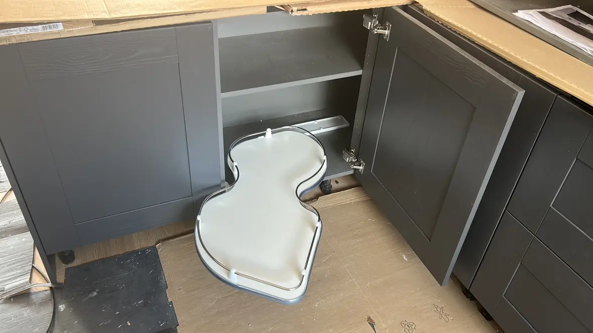 Corner cupboard open with a pull-out corner storage tray