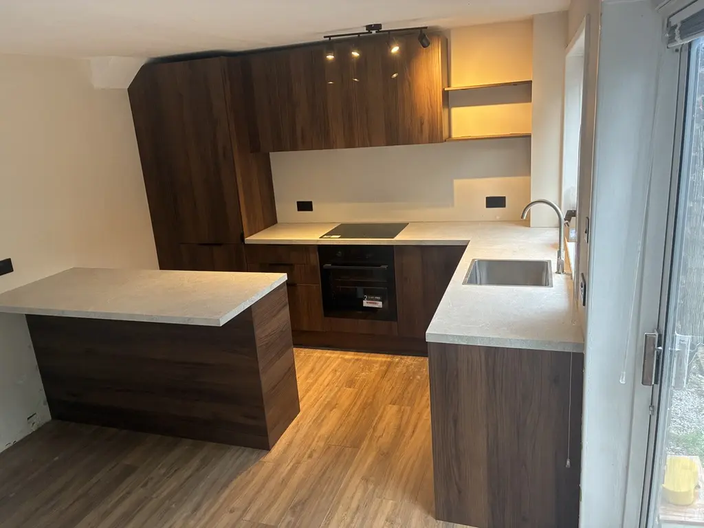 Finished walnut-effect handleless kitchen with peninsula and built-in oven