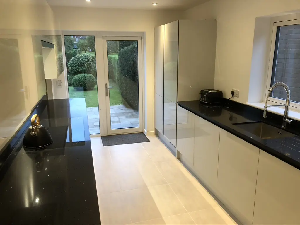 White gloss handleless galley with black quartz worktops and garden doors