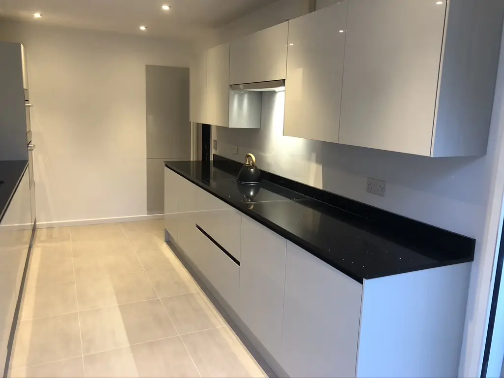 White gloss handleless run with black sparkle quartz worktop