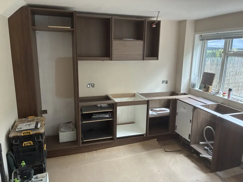 Walnut-effect carcasses and tall housing fitted, no doors or worktops yet
