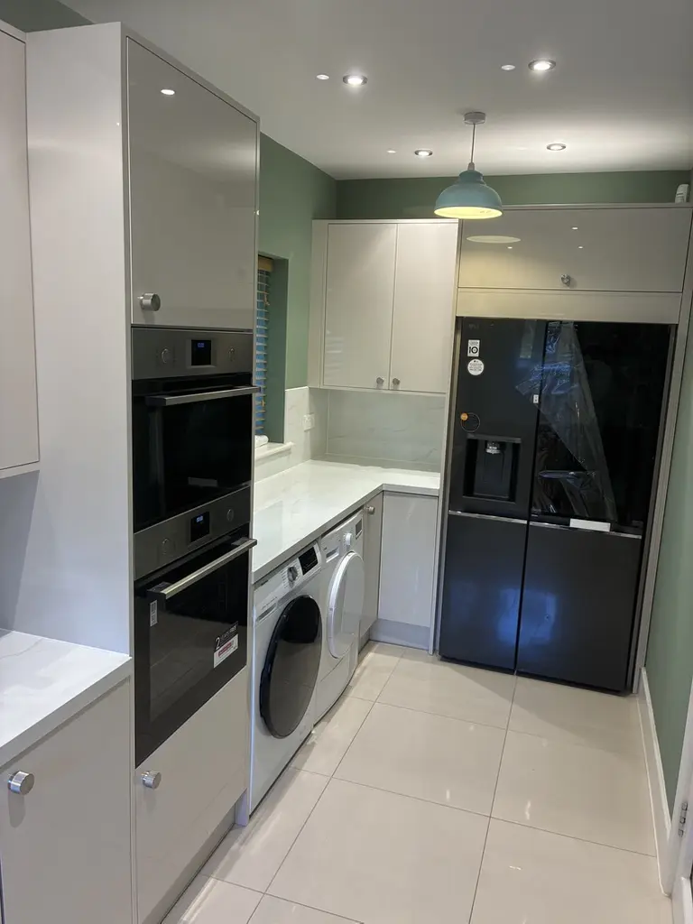 Double ovens in tall housing and an American fridge freezer framed by units
