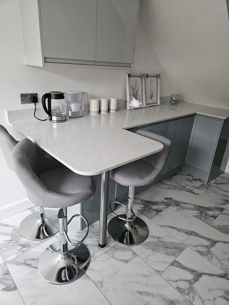 Curved white sparkle worktop breakfast bar with grey stools