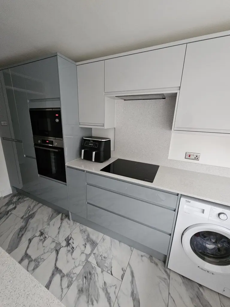 Grey gloss handleless units with integrated ovens and a sparkle quartz worktop