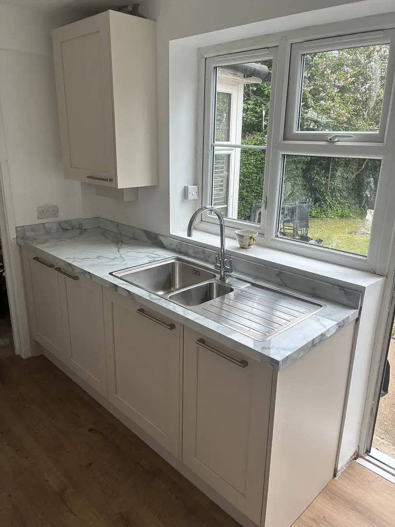 Cream shaker base units with an inset stainless sink and marble-effect worktop