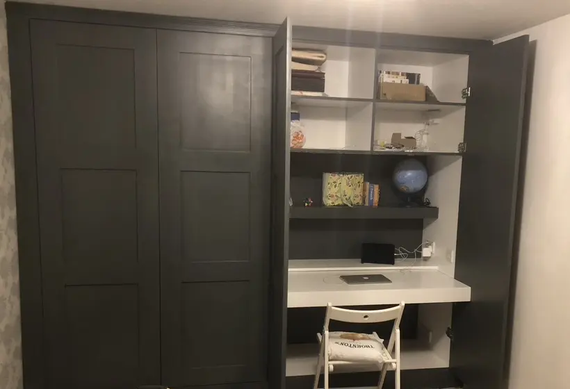 Wardrobe doors open to reveal a white desk, shelves and a laptop