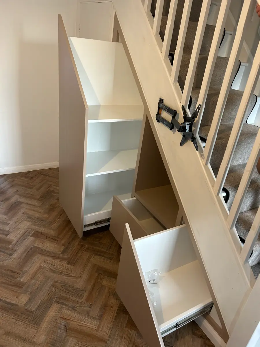 Under-stair storage open, showing shelves and a deep pull-out drawer
