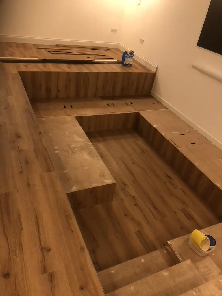Sunken lounge under construction, storage lids with finger holes in the seat tops