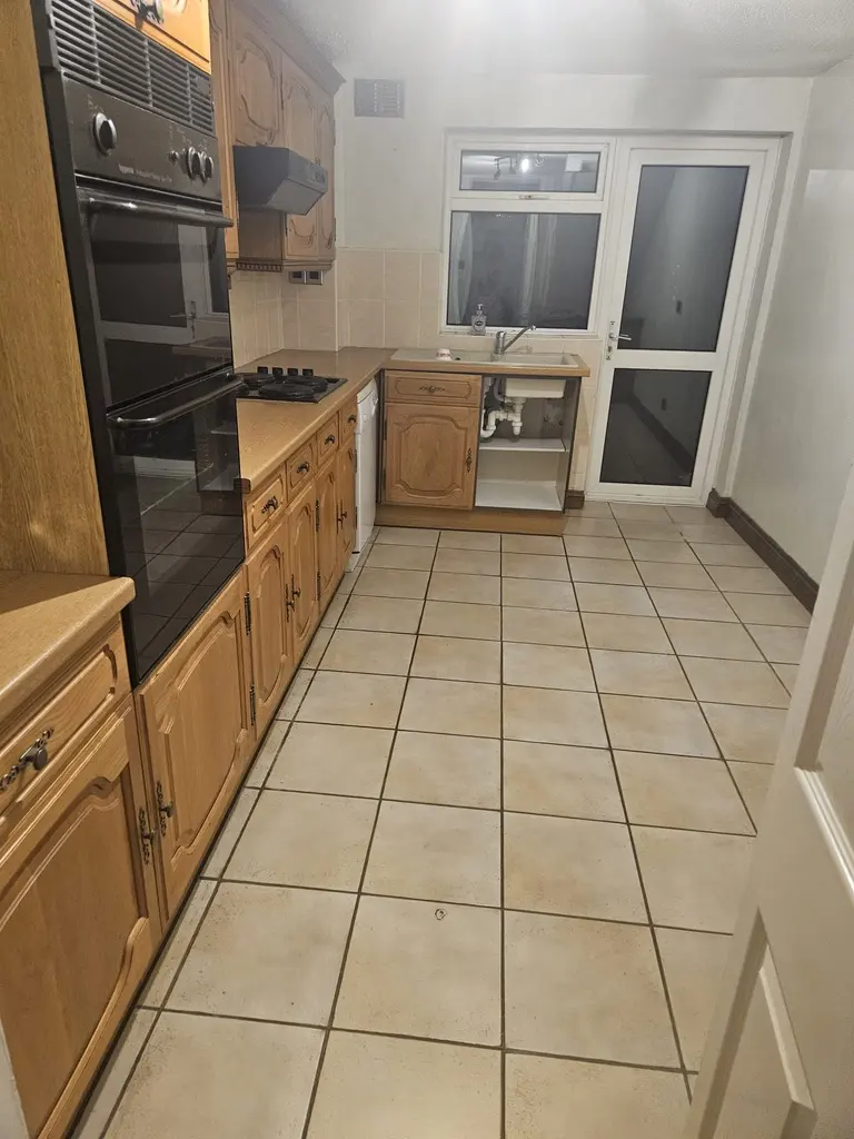 Old oak-effect kitchen with beige floor tiles before the refit