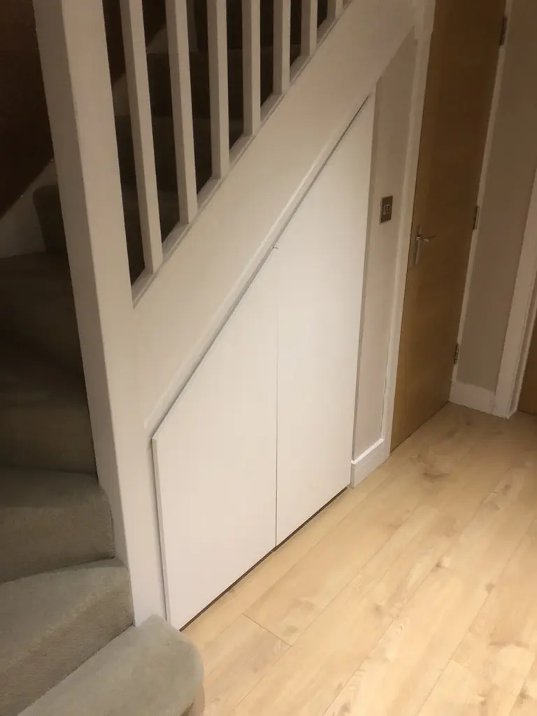 Under-stair storage closed, two flush white doors under the banister