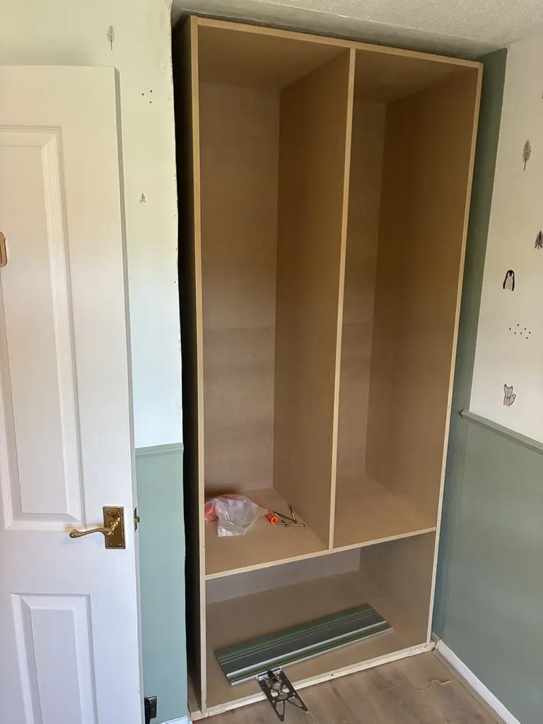 MDF wardrobe carcass fitted into an alcove beside a bedroom door