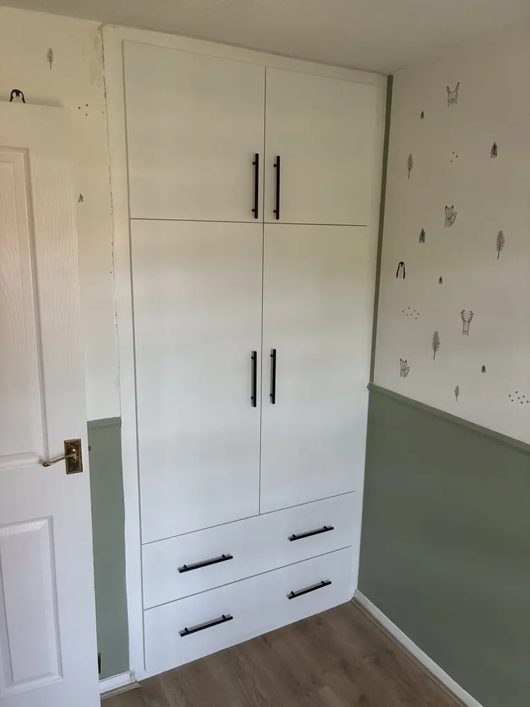 White built-in wardrobe with four doors, two drawers and black bar handles